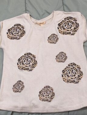 beige Mesh+Love sweater featuring a leopard print rose applique on the chest.